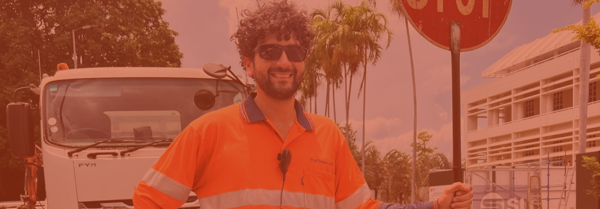 Traffic Controller Marco stand with a stop bat in front of a truck on a work site in Darwin.